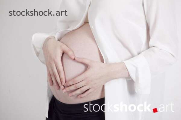 A happy future mother with a heart on her pregnancy belly - stock image