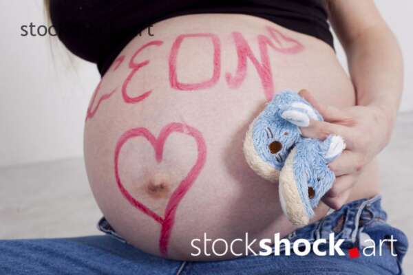 A pregnant belly with a name written on it with lipstick