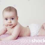 A happy baby on a pink, pastel blanket – stock image
