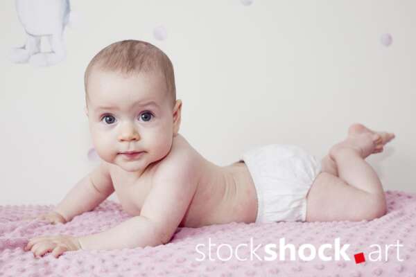 A happy baby on a pink, pastel blanket – stock image