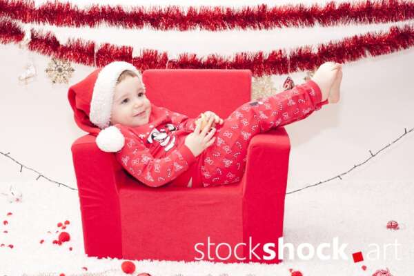 A child in a Santa Claus costume in an armchair. Christmas holidays - stockshock image