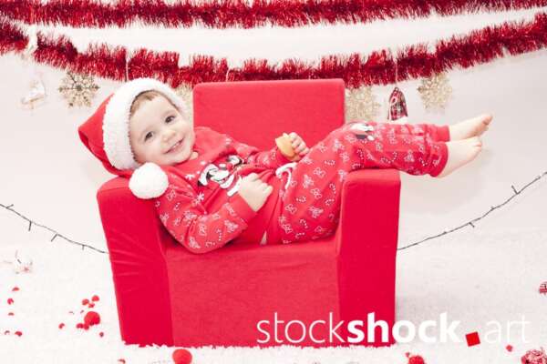 A child in a Santa Claus costume in an armchair. Christmas holidays - stockshock image