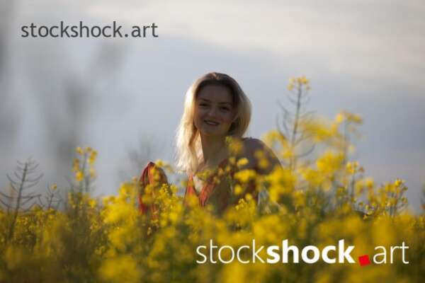 Girl in a red dress in yellow rapeseed, portrait, stock image