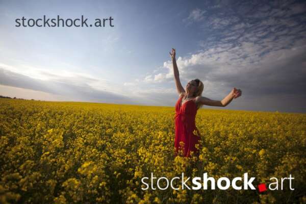 Girl in a red dress in yellow rapeseed, portrait, stock image
