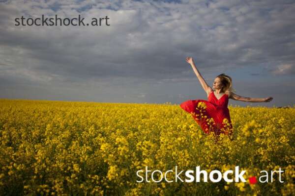 Girl in a red dress in yellow rapeseed, portrait, stock image
