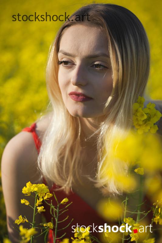 Girl in a red dress in yellow rapeseed, portrait, stock image