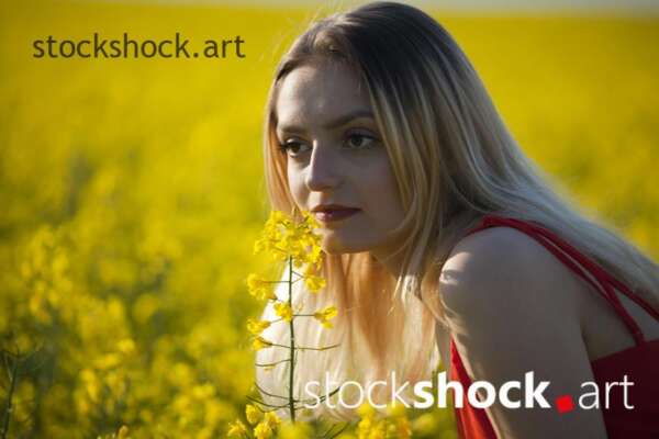 Girl in a red dress in yellow rapeseed, portrait, stock image