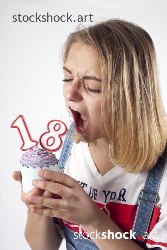 18 birthday, girl on white background with cookie and birthday candles - stock image