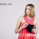 A girl in a red dress with a bag in her hand - stock image