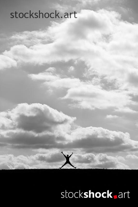 Happy person with open arms jumping against the background of clouds, b&w, stock image
