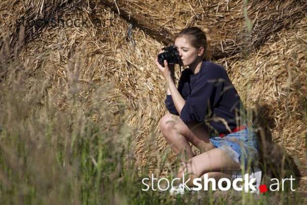 Girl with camera on straw bales, stock image