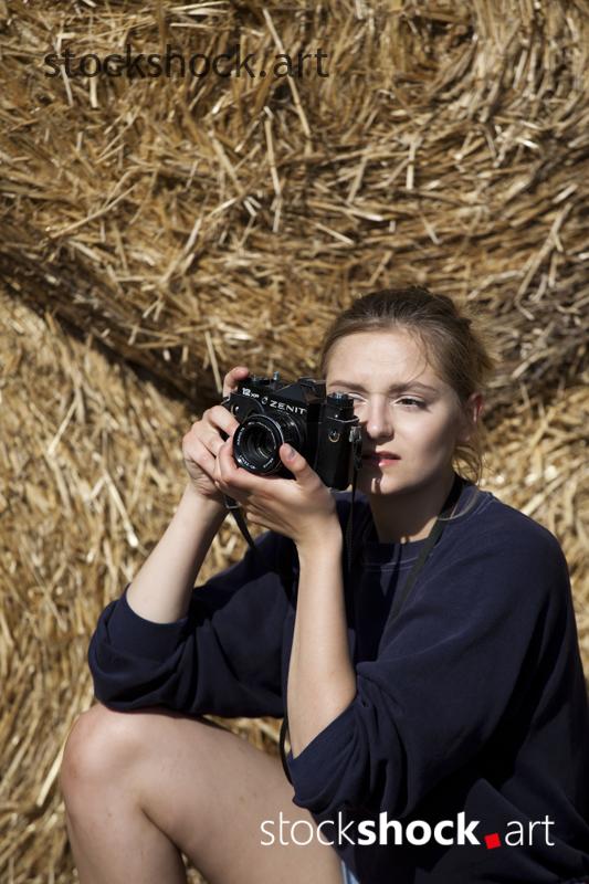 Girl with camera on straw bales, stock image