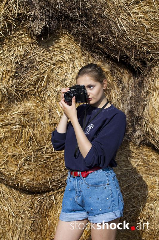 Girl with camera on straw bales, stock image