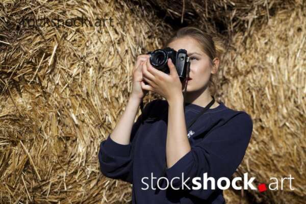 Girl with camera on straw bales, stock image
