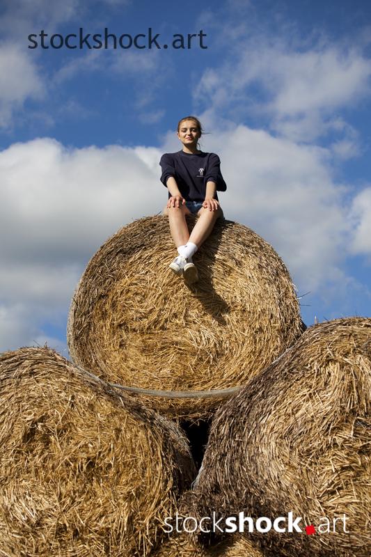 Woman on straw bales - stock image