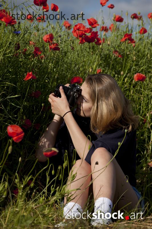 Woman with a Camera, red poppies - stock image