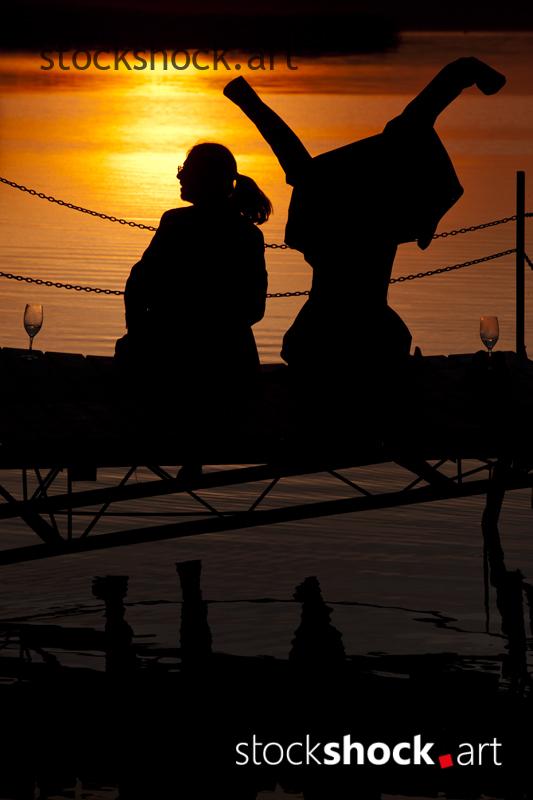 A couple on the pier against the background of the setting sun