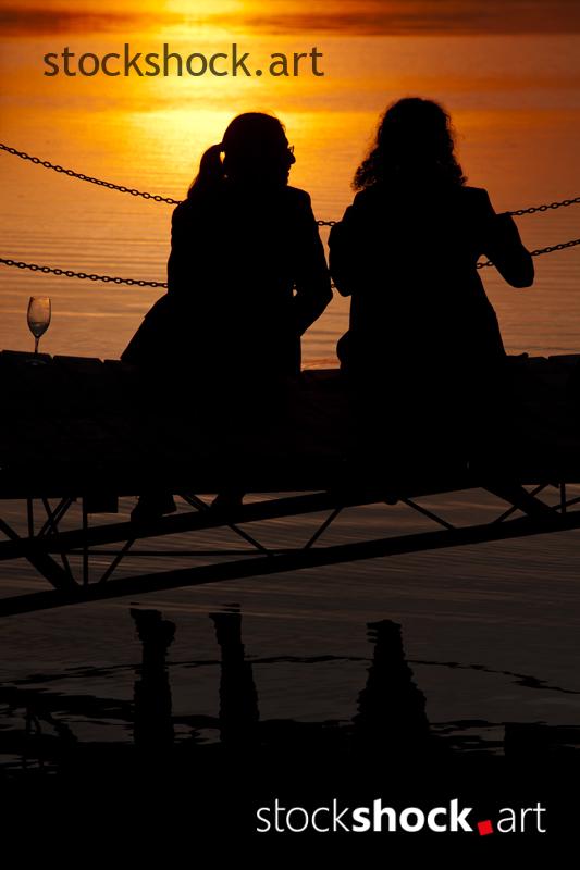 A couple on the pier against the background of the setting sun