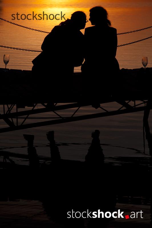 A couple on the pier against the background of the setting sun