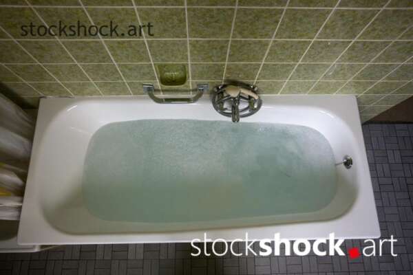 An old bathtub filled with water in a green bathroom