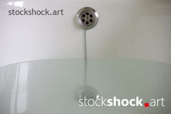 A stopper on a chain in a bathtub with water - stock imageÂ