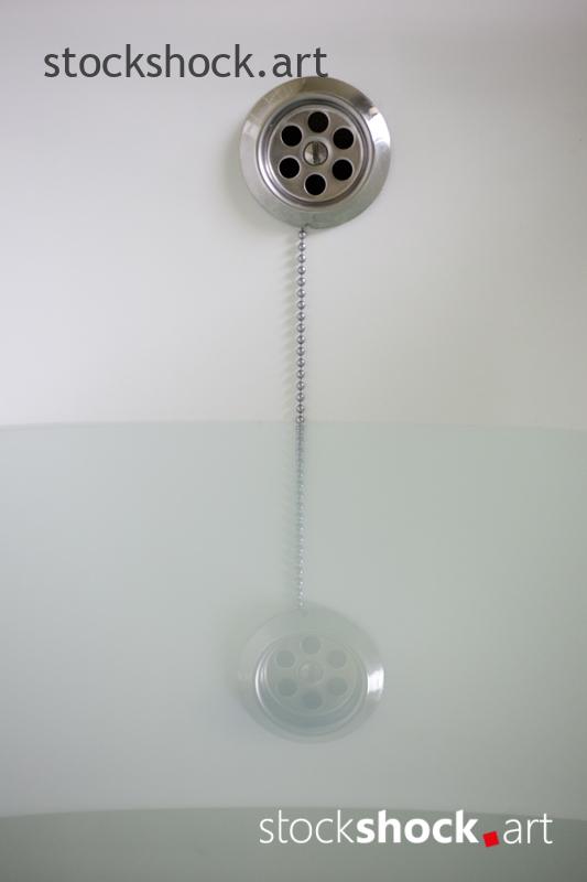 A stopper on a chain in a bathtub with water - stock imageÂ