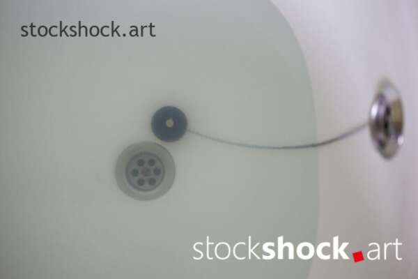 A stopper on a chain in a bathtub with water - stock image 