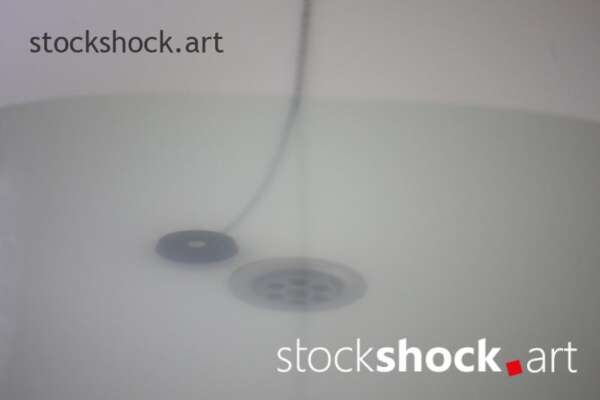 A stopper on a chain in a bathtub with water - stock imageÂ