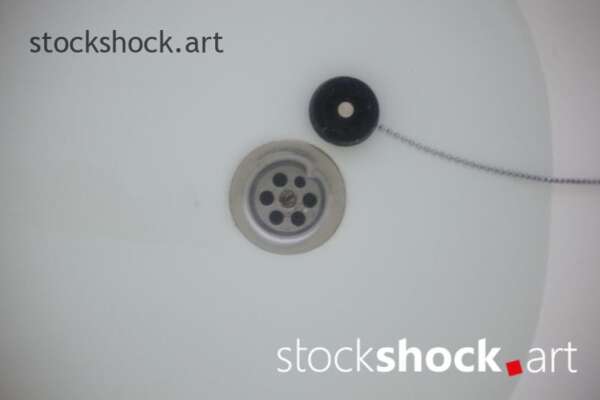 A stopper on a chain in a bathtub with water - stock imageÂ