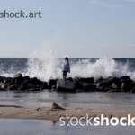 Girl on the rocks on the seashore against the background of the wave