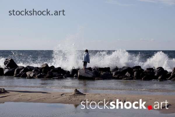 Girl on the rocks on the seashore against the background of the wave