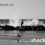 Girl on the rocks on the seashore against the background of the wave