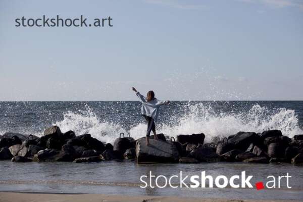 Girl on the rocks on the seashore against the background of the wave