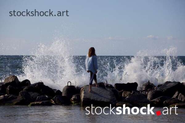 Girl on the rocks on the seashore against the background of the wave