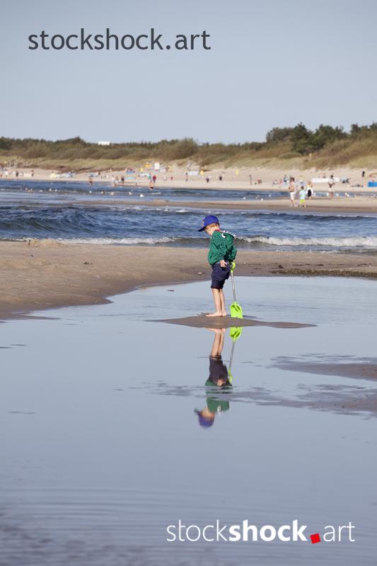 Little boy with a paddle on the seashore
