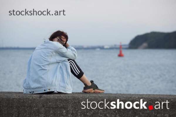 Girl sitting on a wall looking at the sea