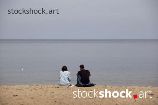The couple is sitting by the sea