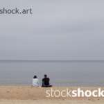 The couple is sitting by the sea