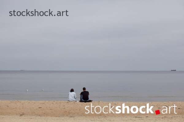 The couple is sitting by the sea