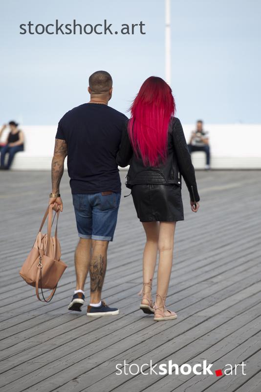 A girl with red hair is walking with her boyfriend on the pier
