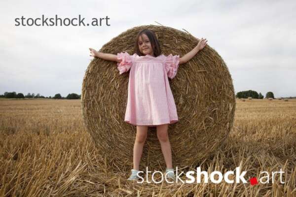 The end of the harvest. Girl standing on the background of a bale, stock photo, jowita niemczyk, stockshock.art