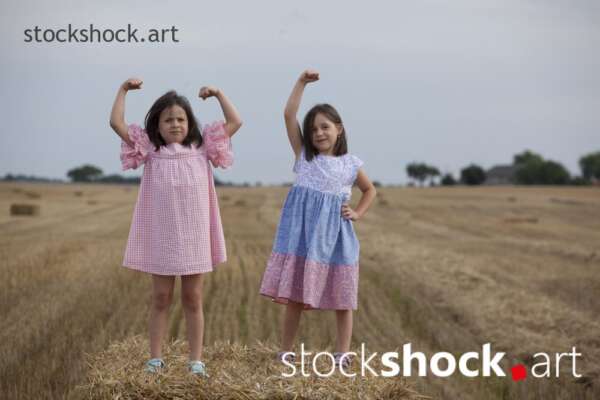 The end of the harvest. Two happy sisters play on bales during the summer harvest - stock photo, jowita niemczyk, stockshock.art