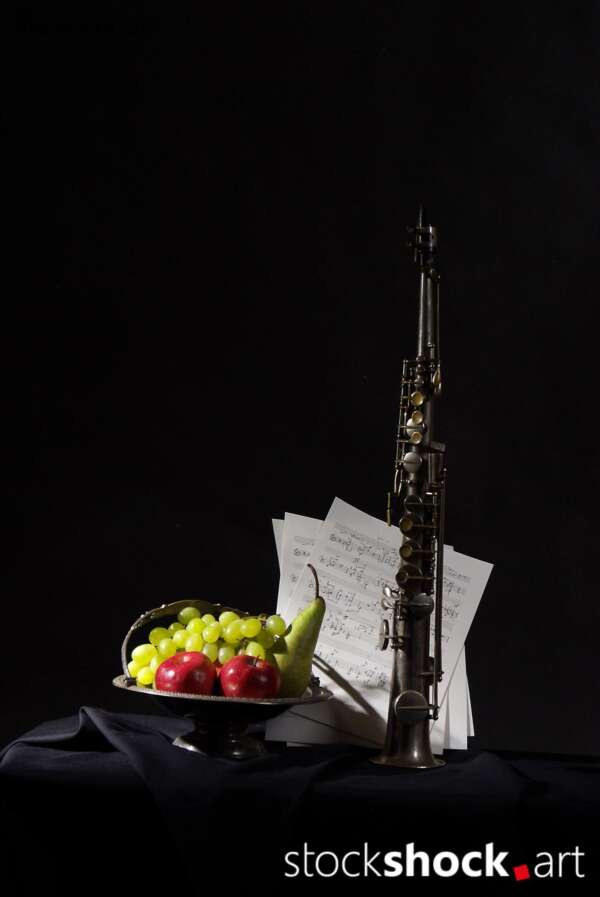 Still life on a black background with fruit on a platter and a clarinet, stock image, jowita niemczyk